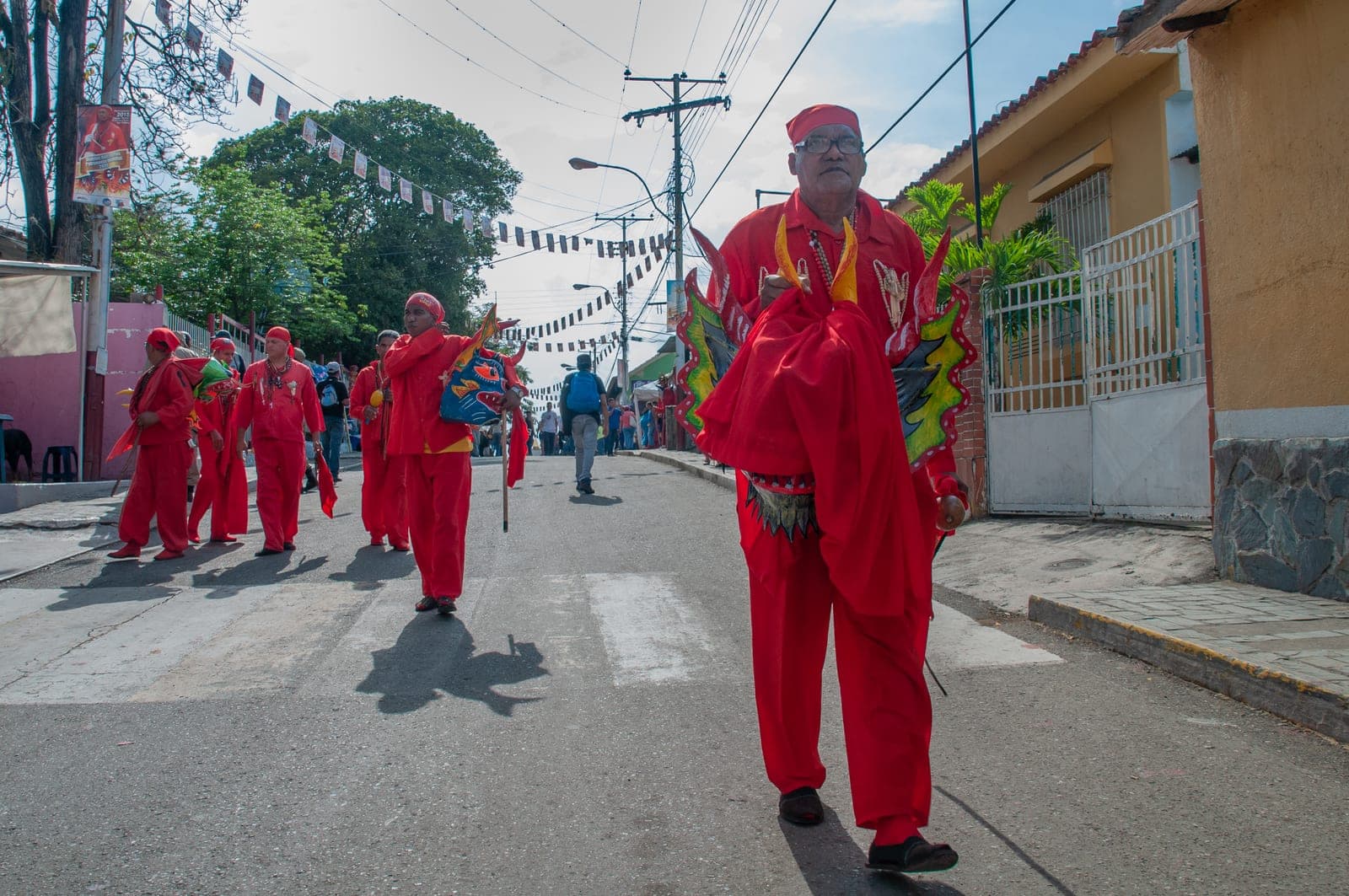 Diablos Danzantes con máscaras y trajes rojos saliendo de la casa de los diablos
