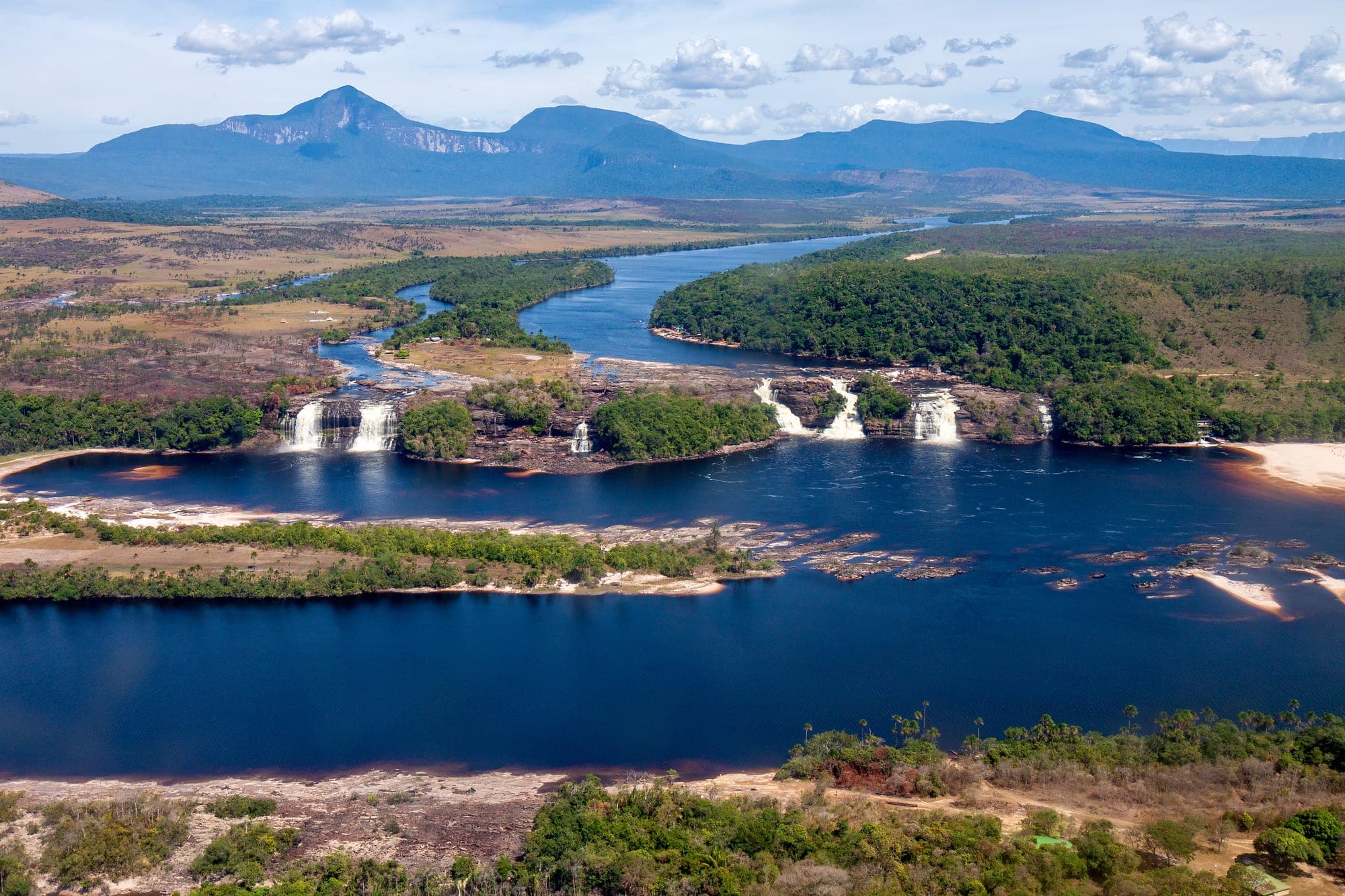 Vista aérea de la laguna de Canaima con sus saltos y los tepuyes al fondo