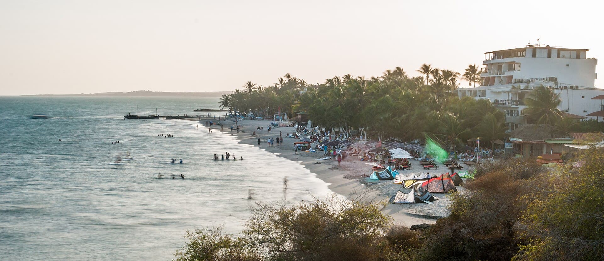Playa El Yaque al atardecer, con cometas de kitesurf sobre la arena y la bahía en calma